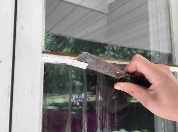 glazier removing old glazing putty from window