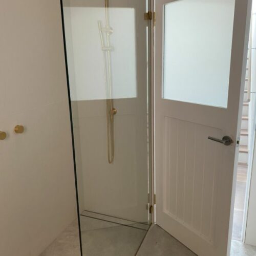 frameless glass shower door with brass fixtures